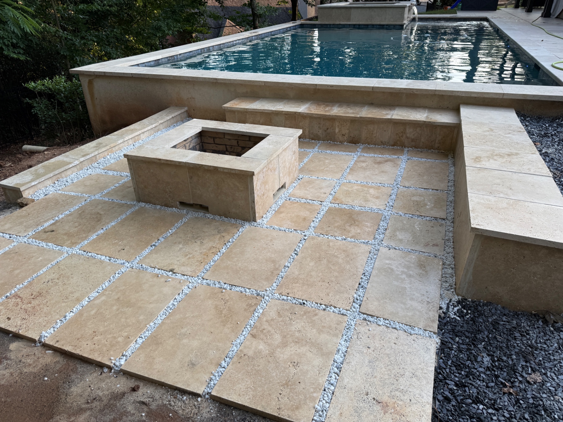 Travertine pavers set in white pebble joints beside a pool