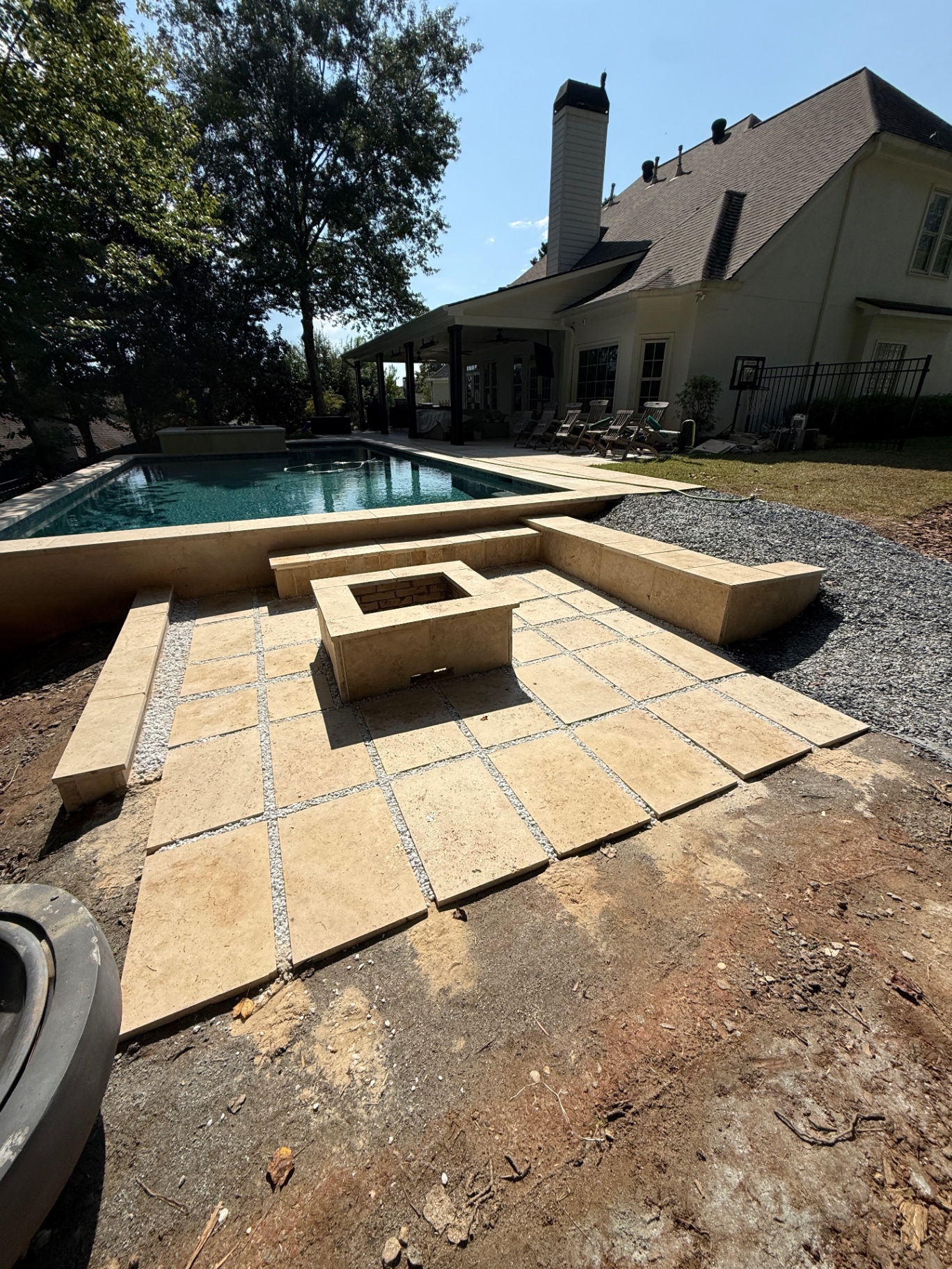 Poolside travertine patio and seat walls built by the Solar Garde crew behind a large Georgia home